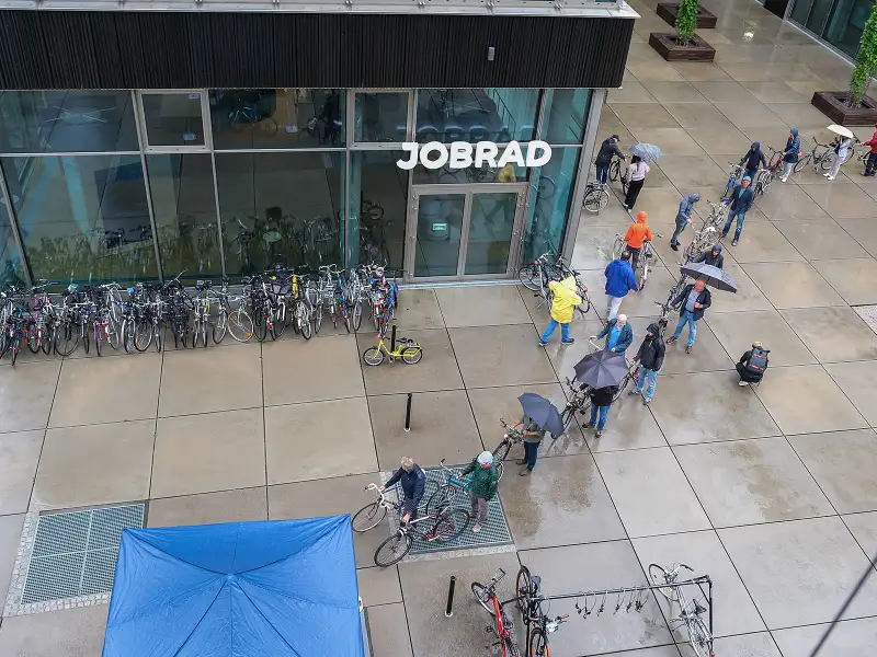 Eine lange Schlange von Menschen mit Fahrrädern und Regenschirmen auf dem JobRad Campus
